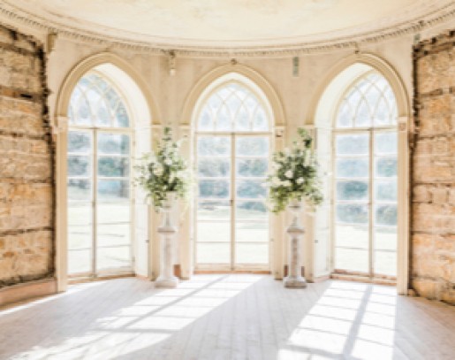 Three brightly lit archway windows with flower bouquets between them