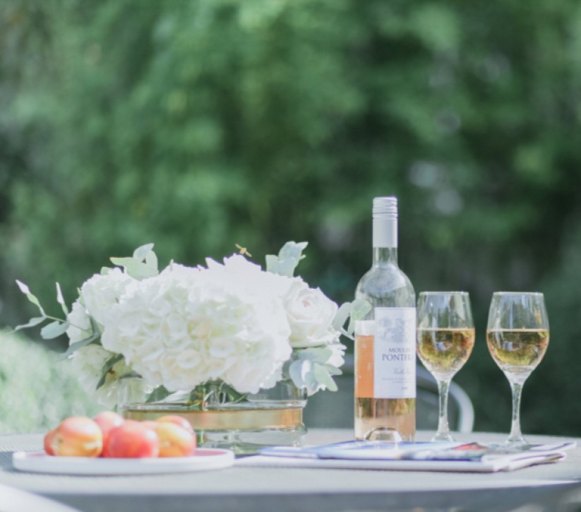 A plate of apples and two glasses of white wine on an outside table