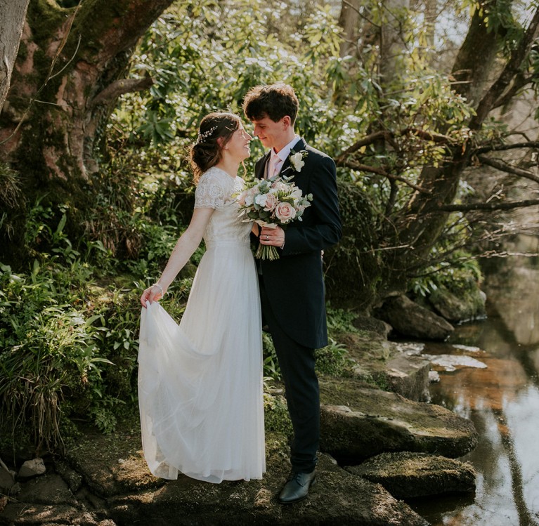 a bride and groom on the riverbank at Brinkburn Northumberland