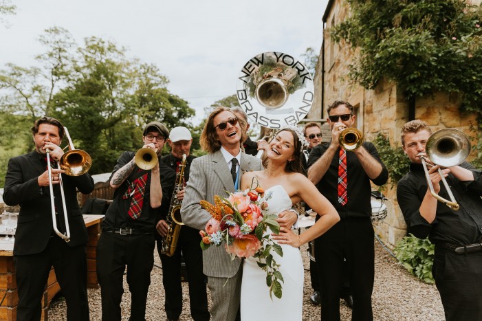 A couple standing with a band outside stables accommodation 