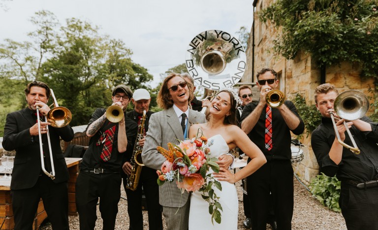 A couple standing with a band outside stables accommodation 