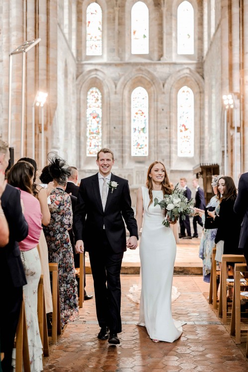 A bride and groom down the aisle Brinkburn Priory in Northumberland