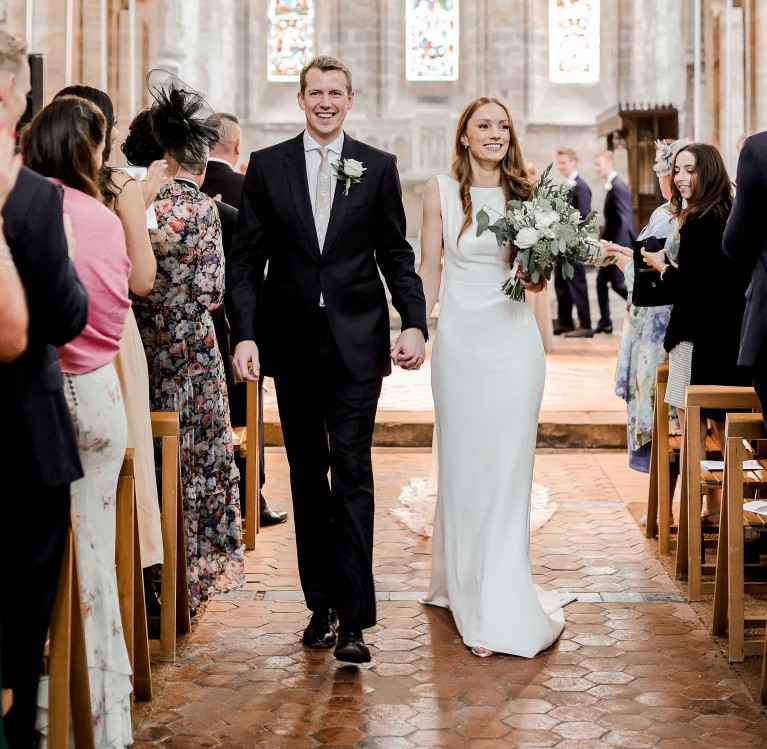 A bride and groom down the aisle Brinkburn Priory in Northumberland