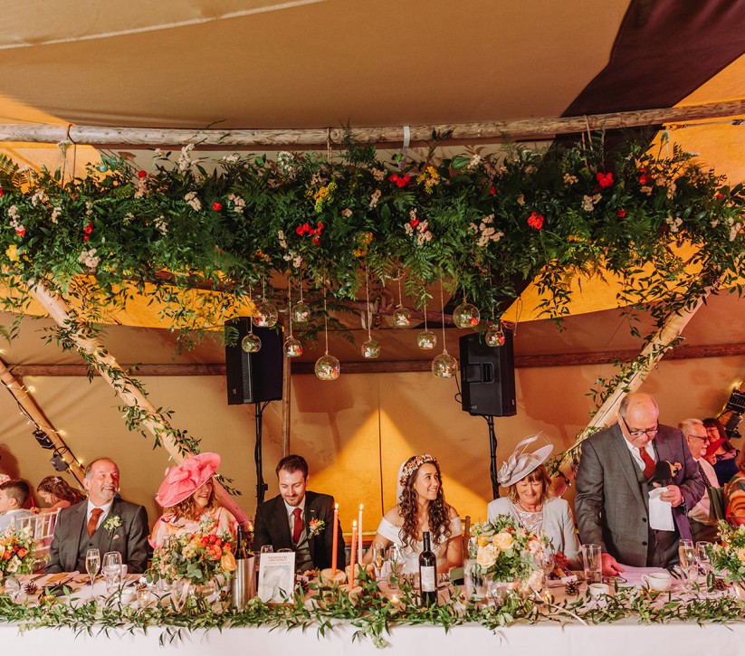 A large white dining table in a giant tipi with a bar in the background